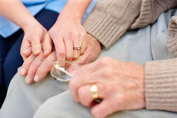 hospice nurse holding elderly mans hand